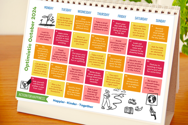 Image of the Action for Happiness calendar with the month October showing, sitting on a desktop.
