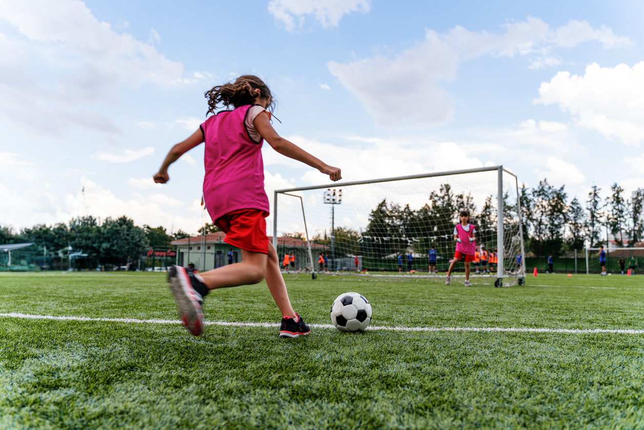 Child playing soccer in an outdoor field.