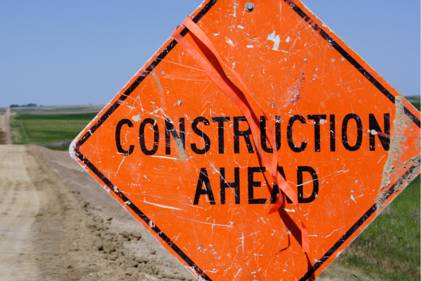 Orange construction ahead sign next to a gravel road