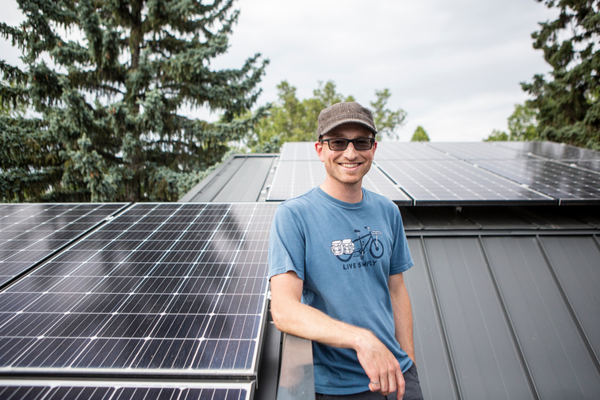 Man standing next to solar panels on roof.